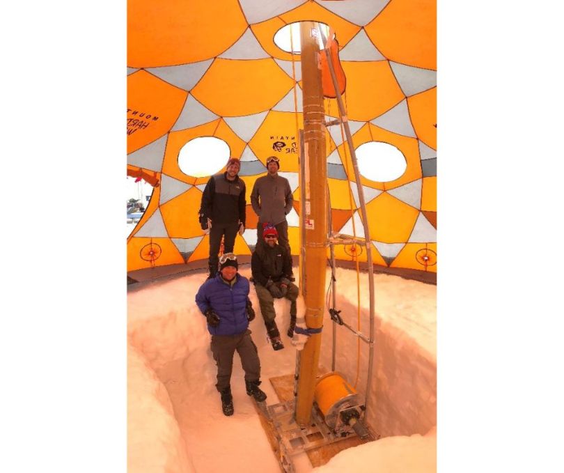 Joey Palmowski and his team pose with the RedWater drill in the cold chamber to test the drill on a block of ice.